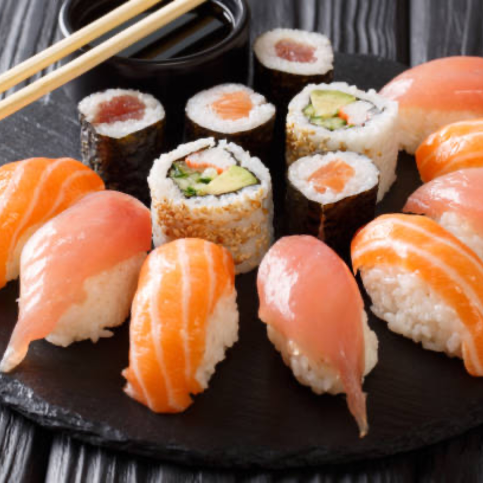 Assortment of Tropical Sushi rolls and nigiri with salmon and tuna, chopsticks, and soy sauce.